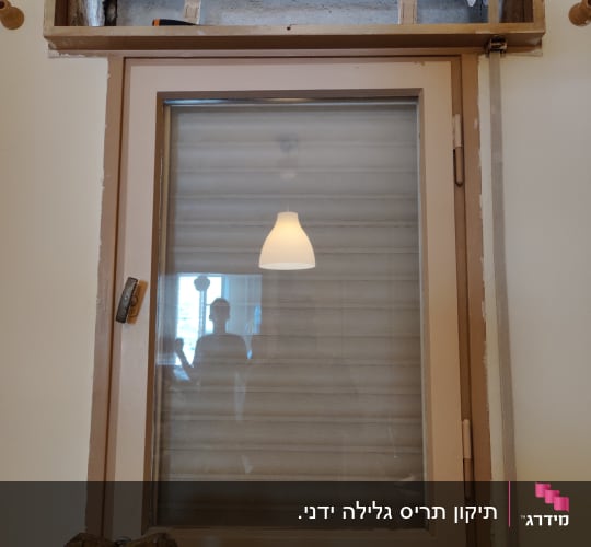 חלון עם תריסים סגורים ומסגרת עץ חשופה